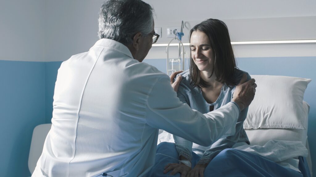 Caring doctor cheering up a patient at the hospital